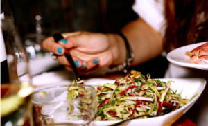 A hand removing food from a vegetable platter.